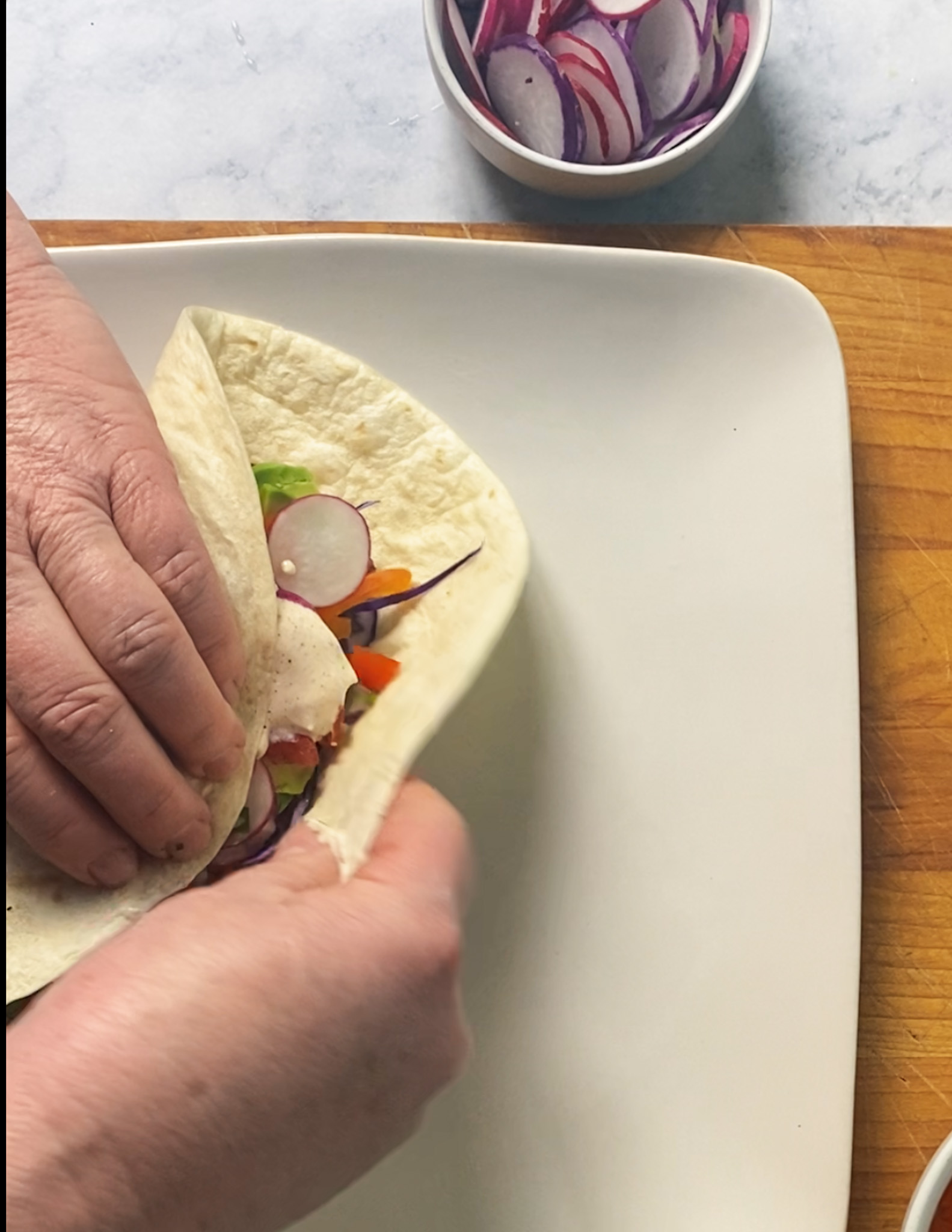 hands rolling the baja fish burrito