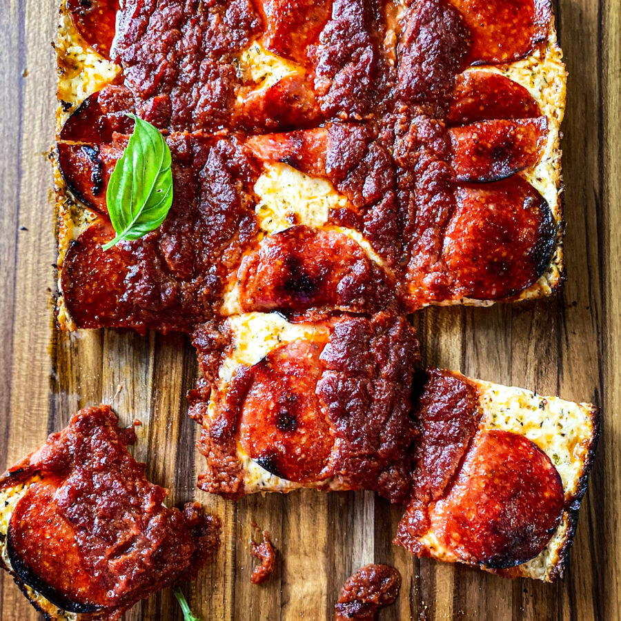 Detroit pepperoni pizza on a cutting board with basil