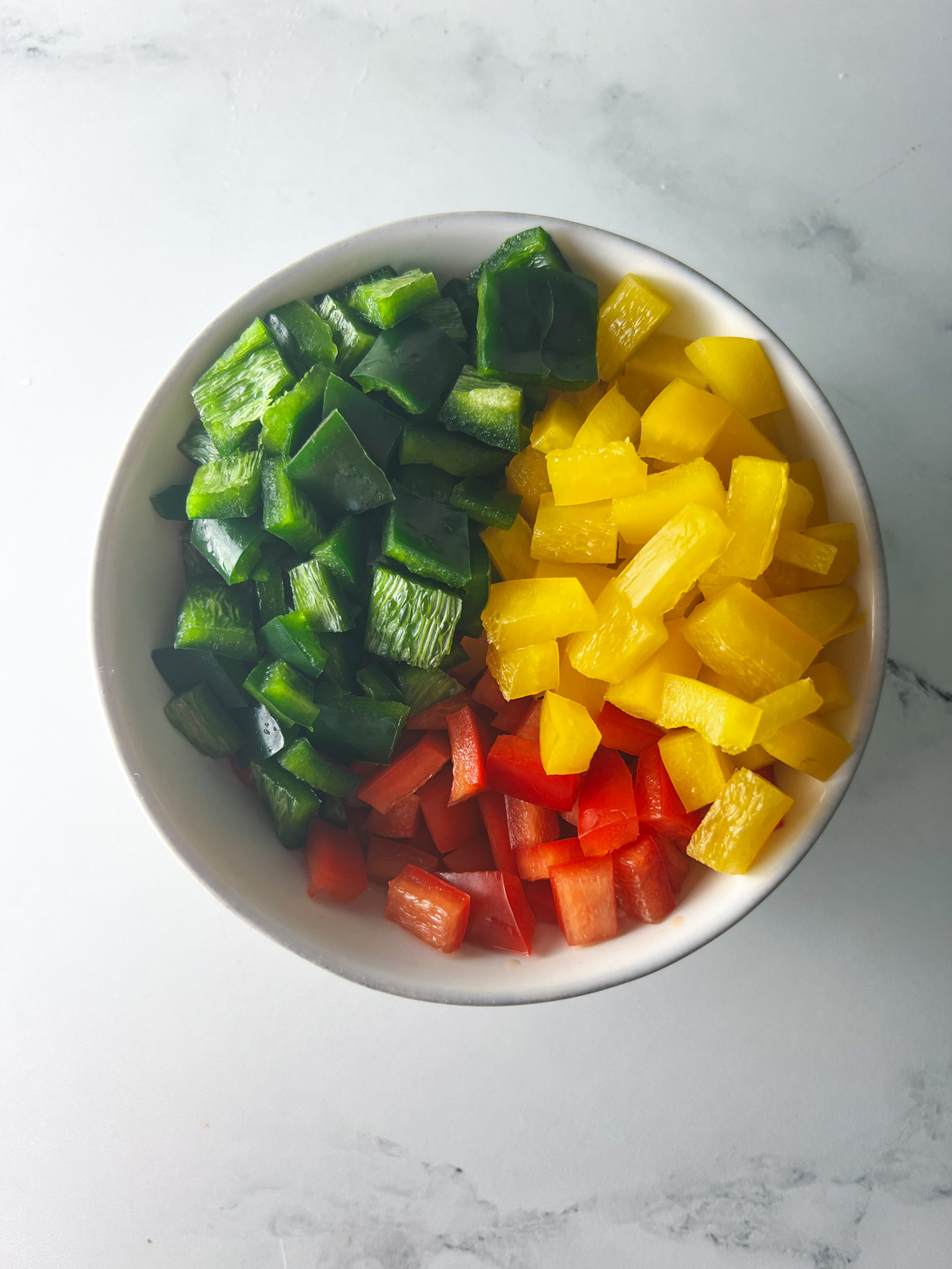 yellow, red and poblano peppers chopped in a white bowl