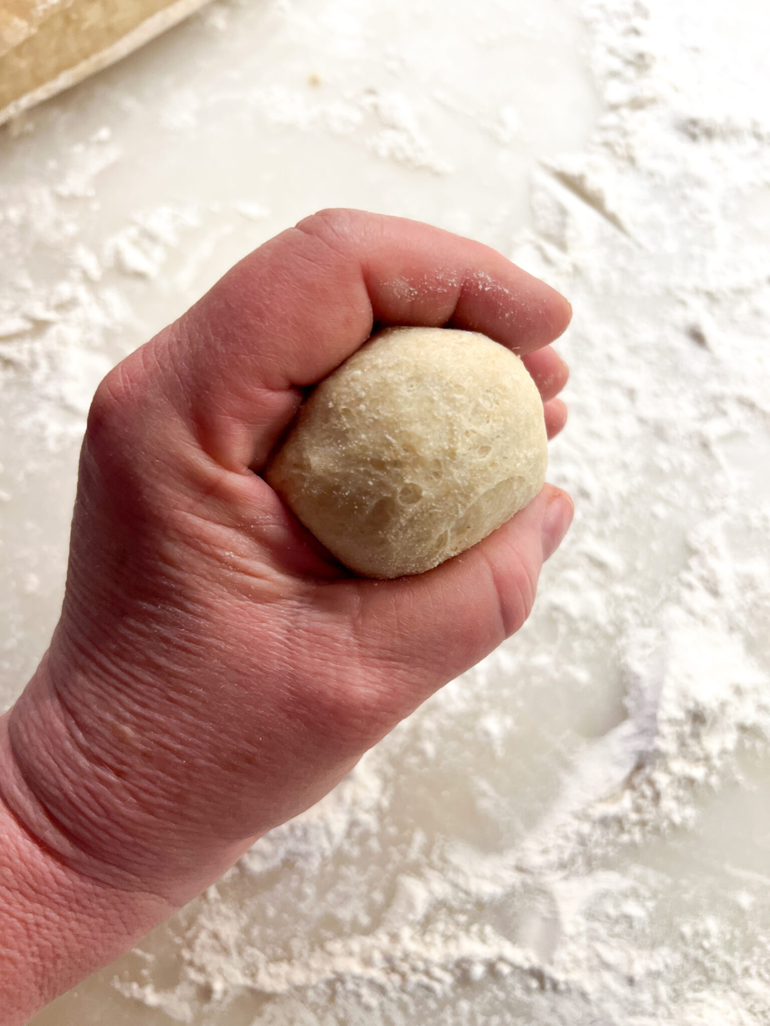 Left hand forming a ball of dough dinner roll