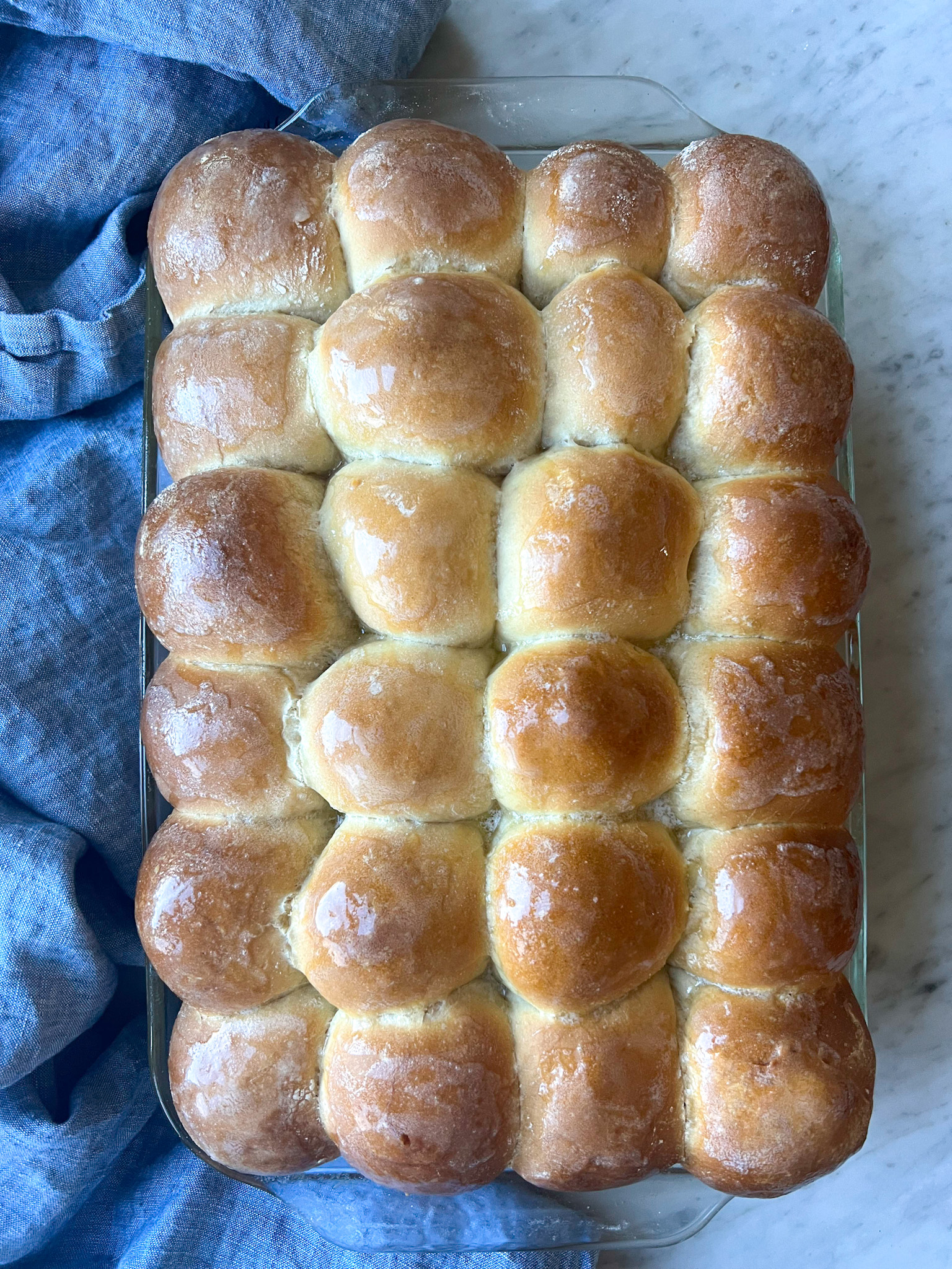 baked rolls with butter over the top and a blue towel
