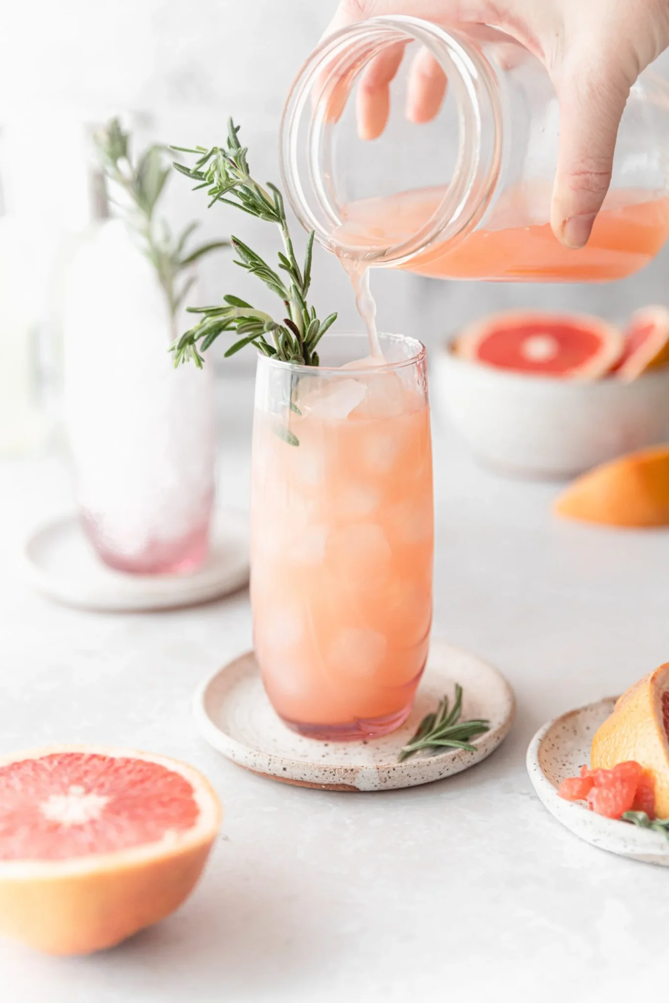 Grapefruit in a dish, a grapegruit mule in a glass with ice and rosemary