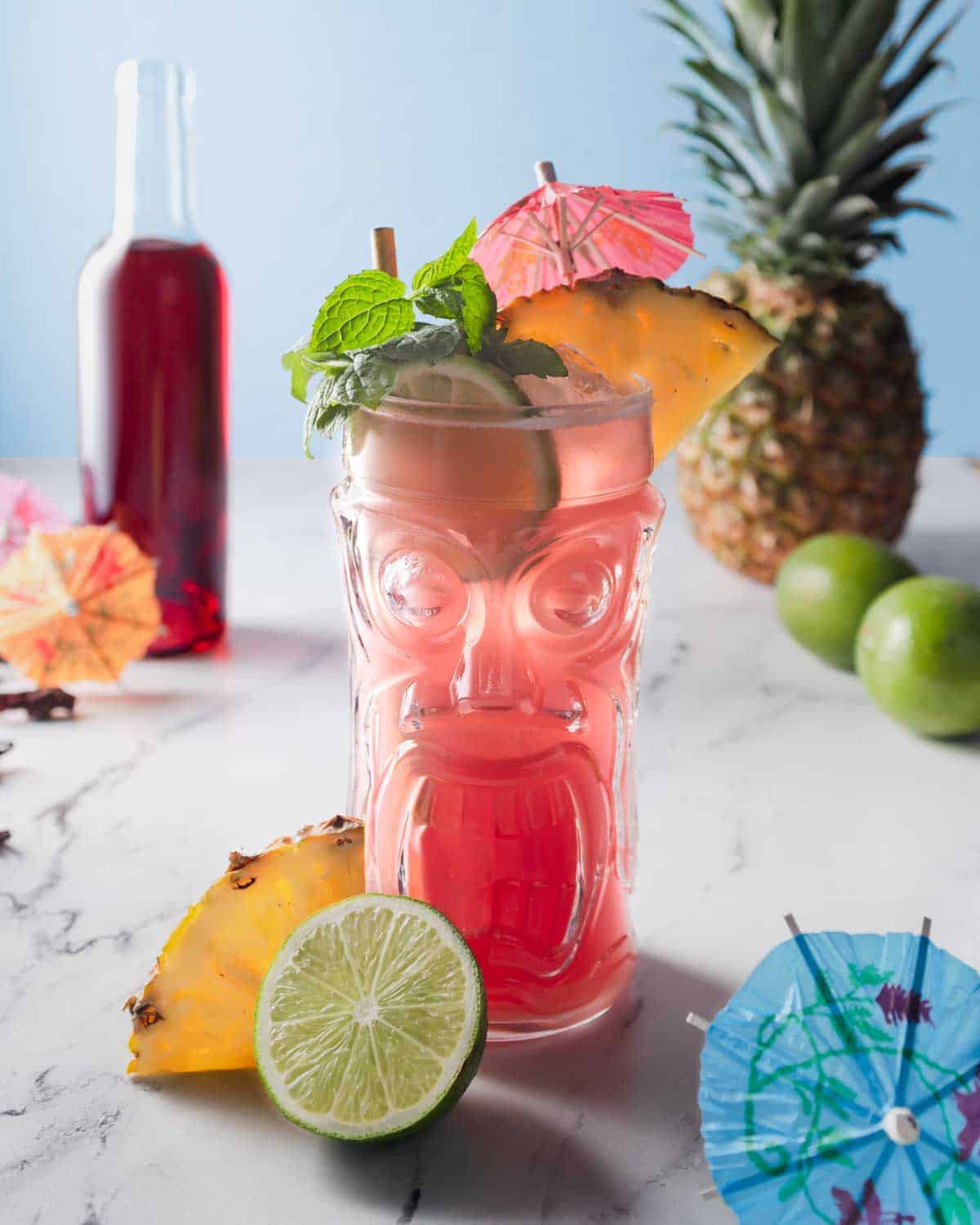 hibiscus rum punch in a tropical glass with lime and pineapple