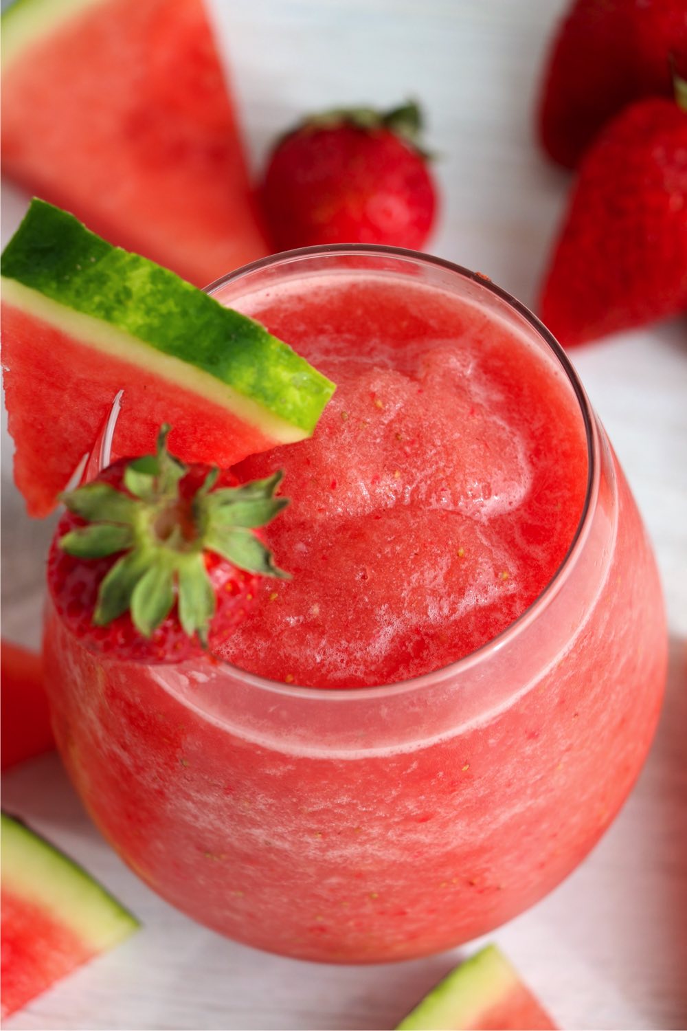 Strawberry and watermellon frosé in a glass with a wedge of watermellon and a strawberry