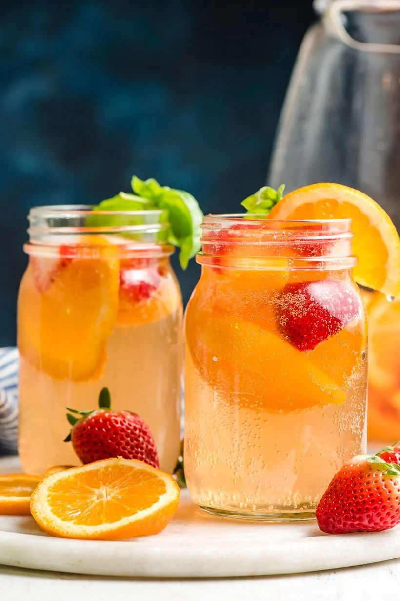 2 white wine sangrias in mason jars with oranges and strawberries