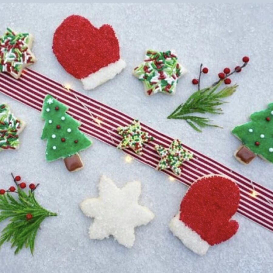 cut out Christmas Cookies laying on table with red ribbon