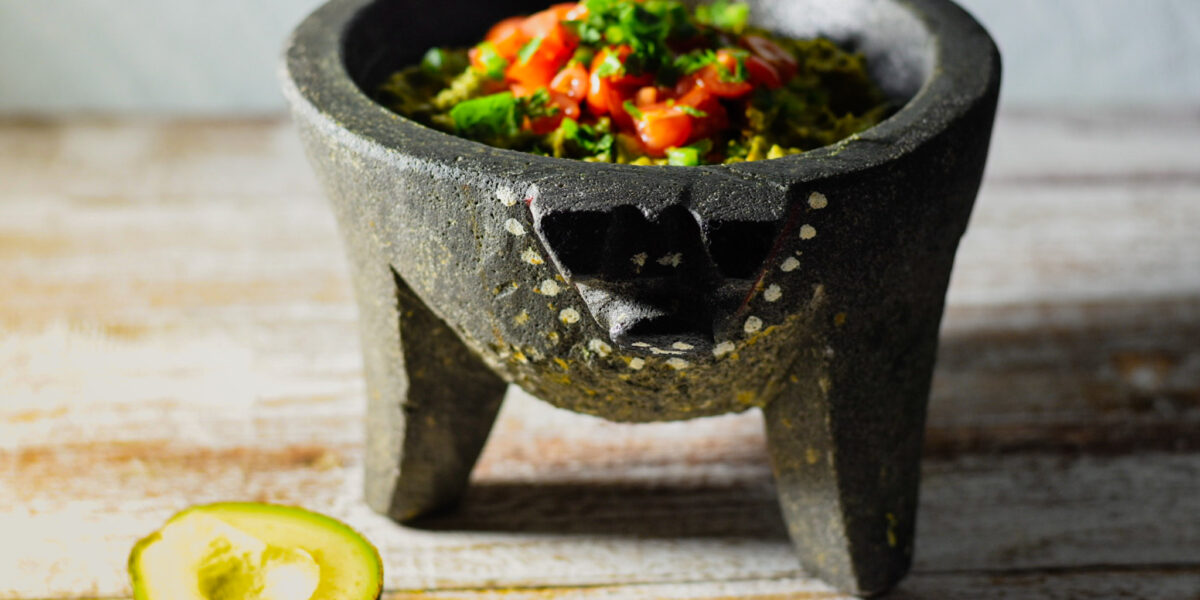Guacamole in a molcajete with an avacodo on counter