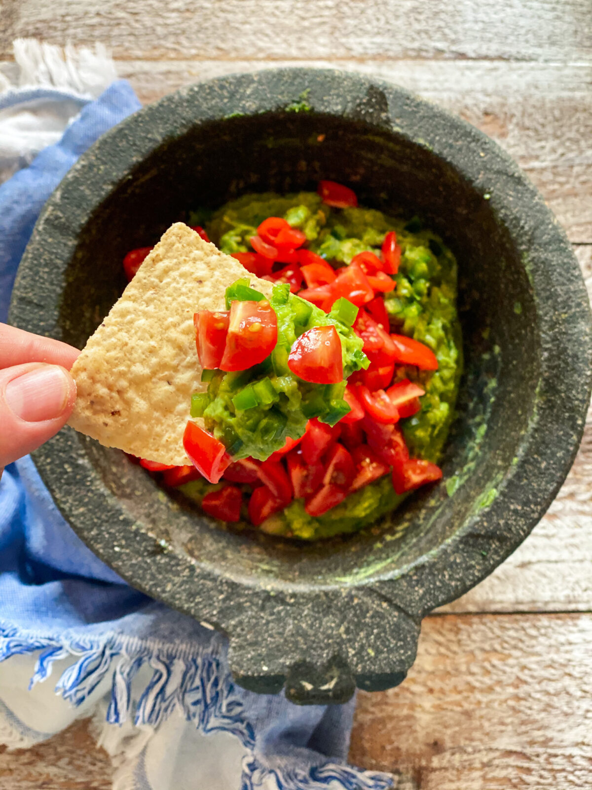 Guacamole in a mocajete with a chip being dipped into it.