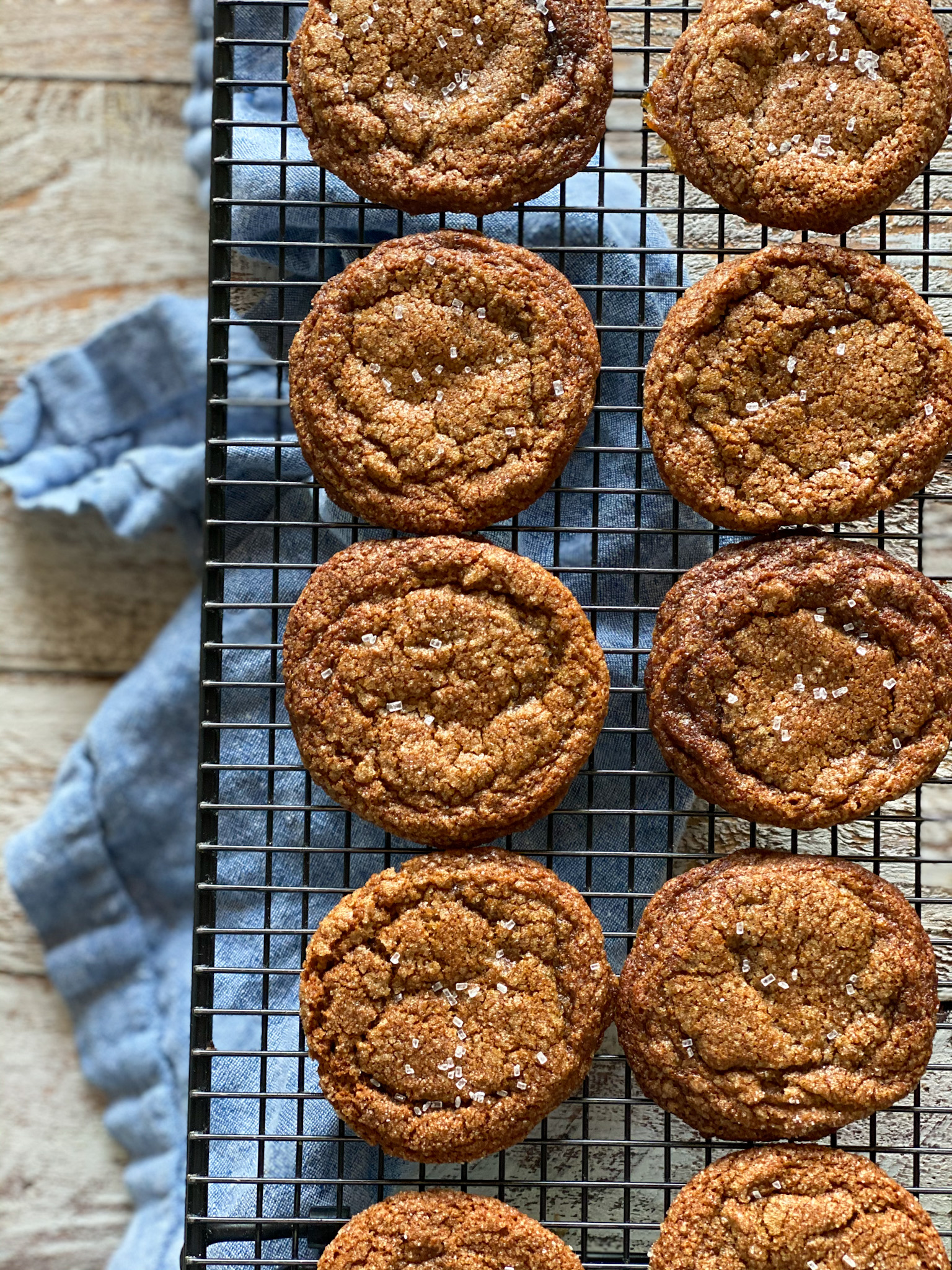 Molasses crinkle cookies on a wire rack over a blue napkin.