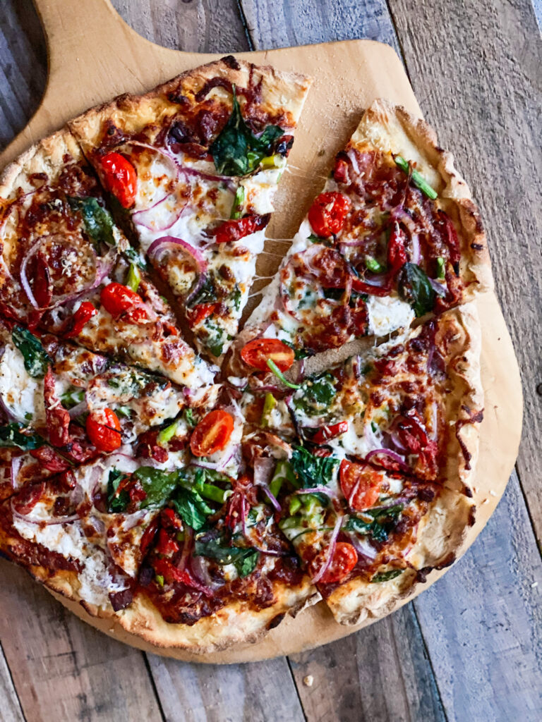 Sourdough Pizza with lots of toppings sliced on a board