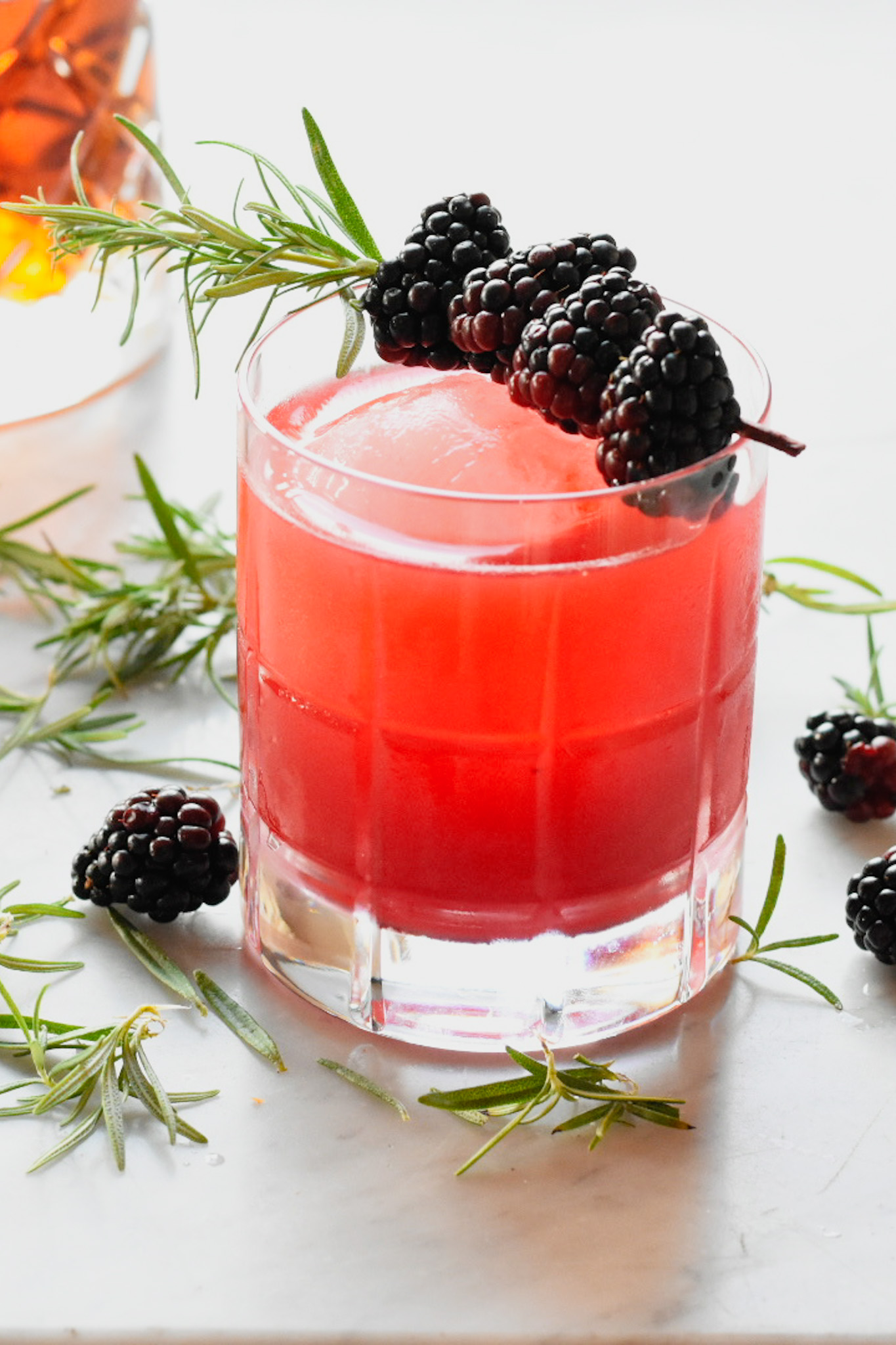 Blackberry bourbon sour in a glass with rosemary and blackberry garnish
