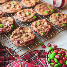 M&Ms in a bowl, plaid napkin, red and white ornament and chocolate chip cookies