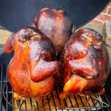 3 beer can smoked chickens on a grill.