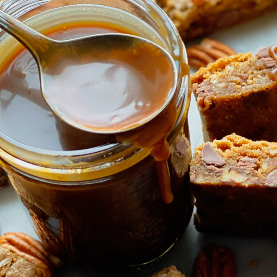 A small mason jar with bourbon salted caramel sauce and blondies