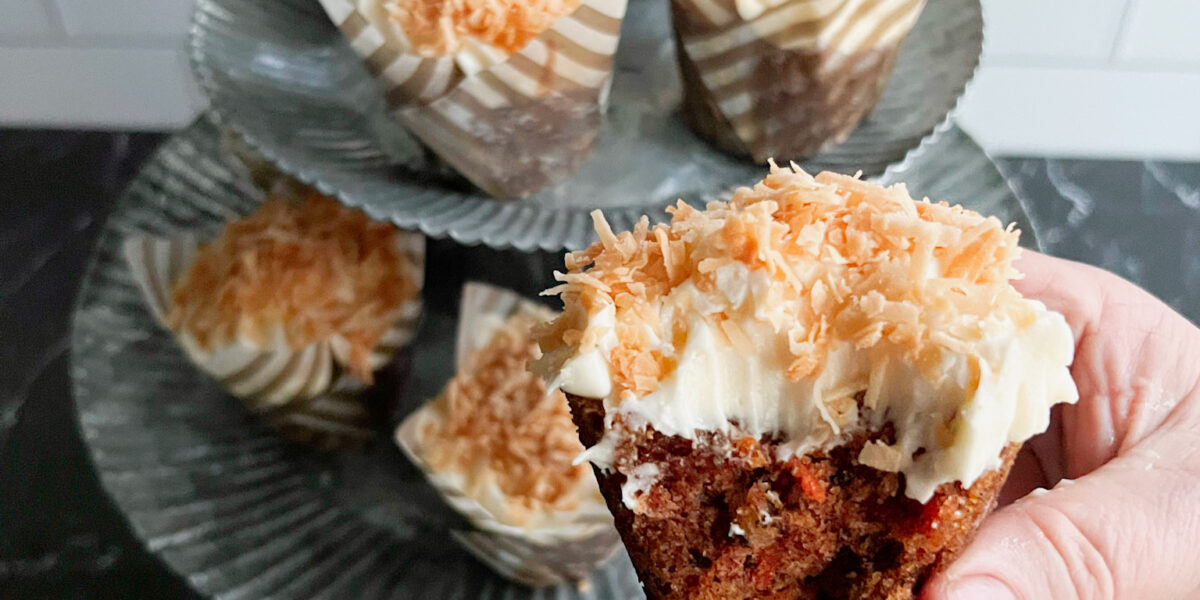 Coconut topped carrot cake cupcakes with a bite out