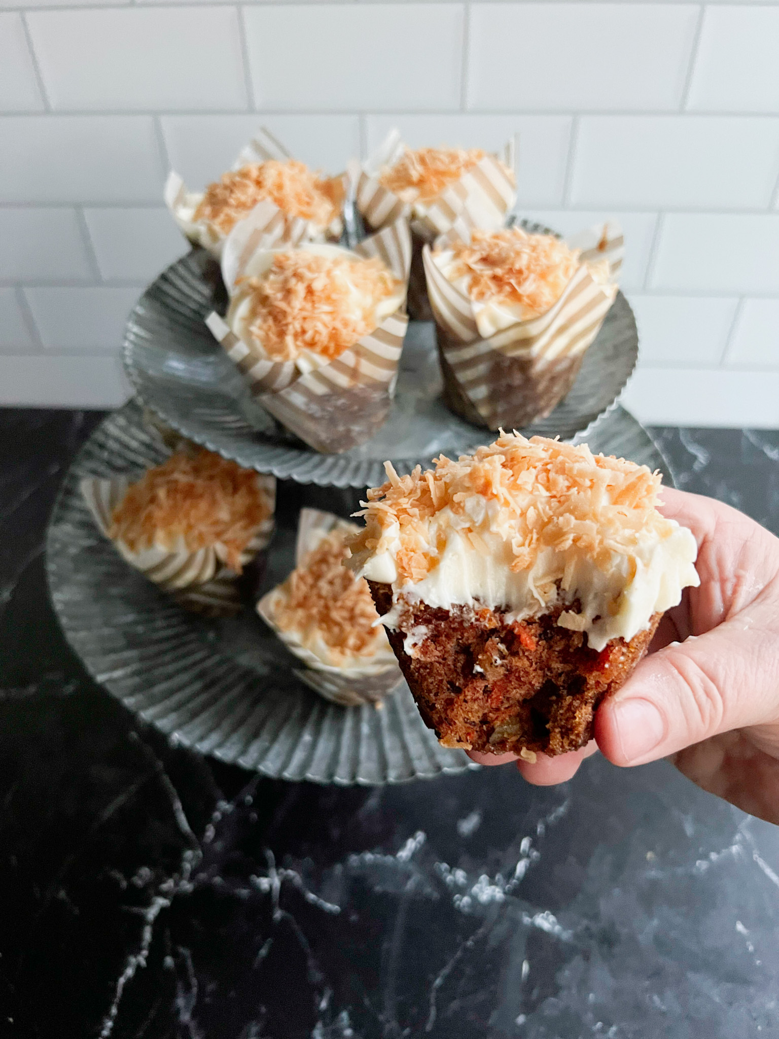 Coconut topped carrot cake cupcakes with a bite out