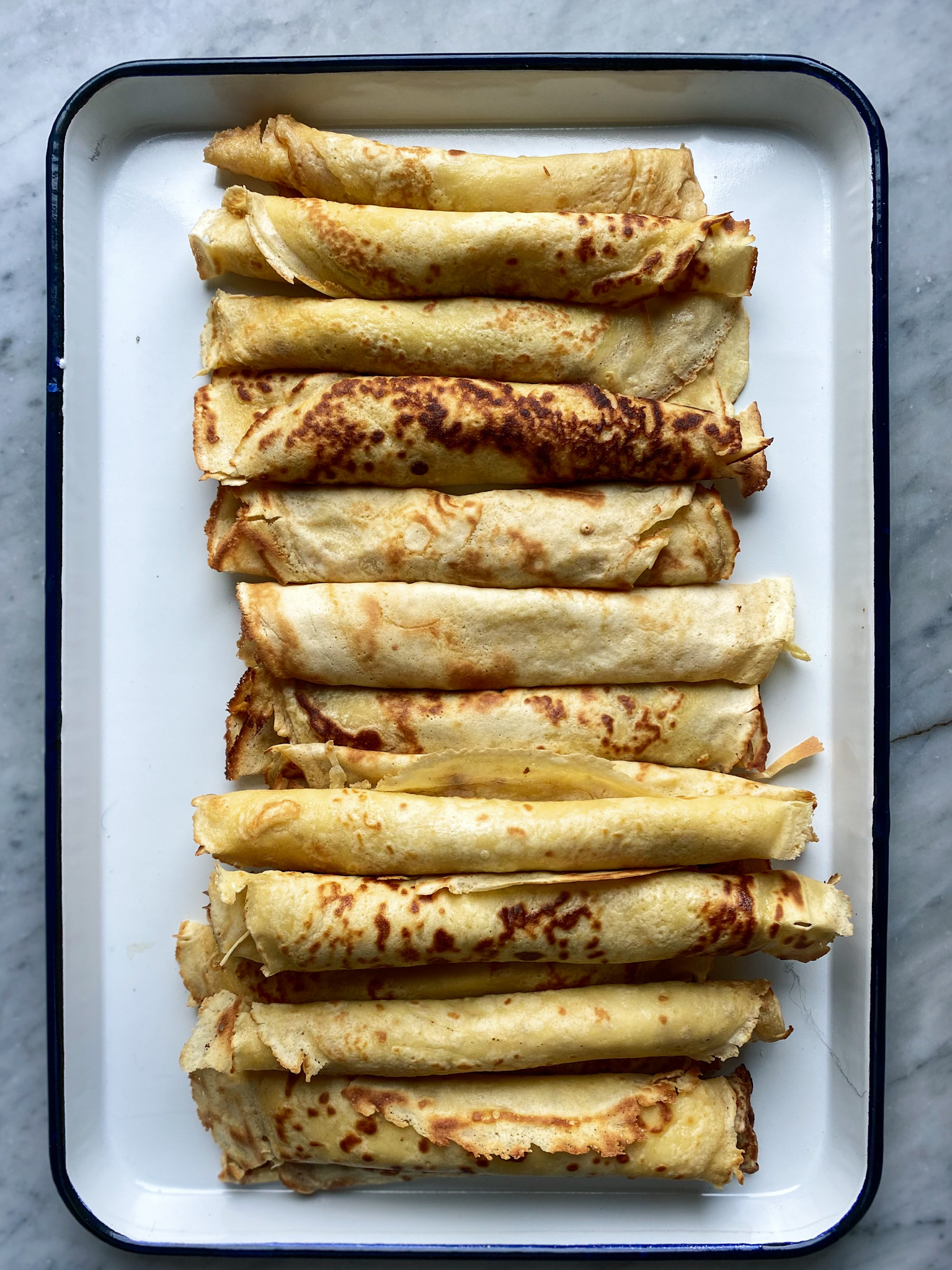 Rolled up crepes on a pan.