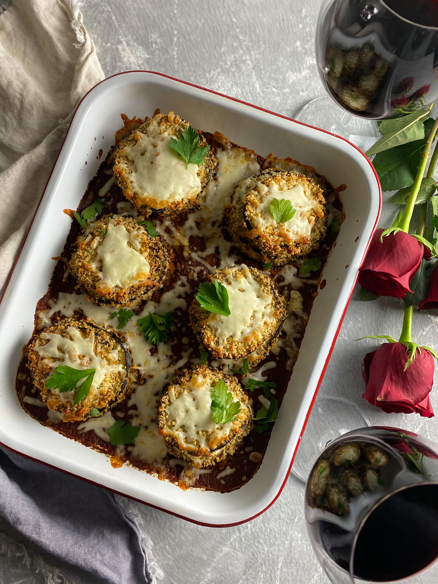 Crispy Baked Eggplant Parmesan in a pan with roses and red wine