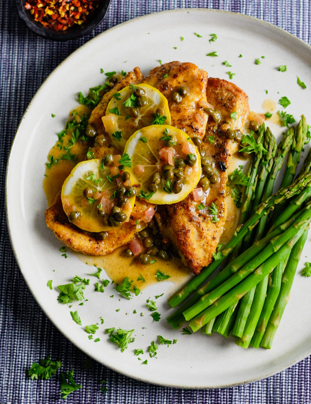 Lemon and caper white wine sauce over chicken with asparagus and hot pepper flakes