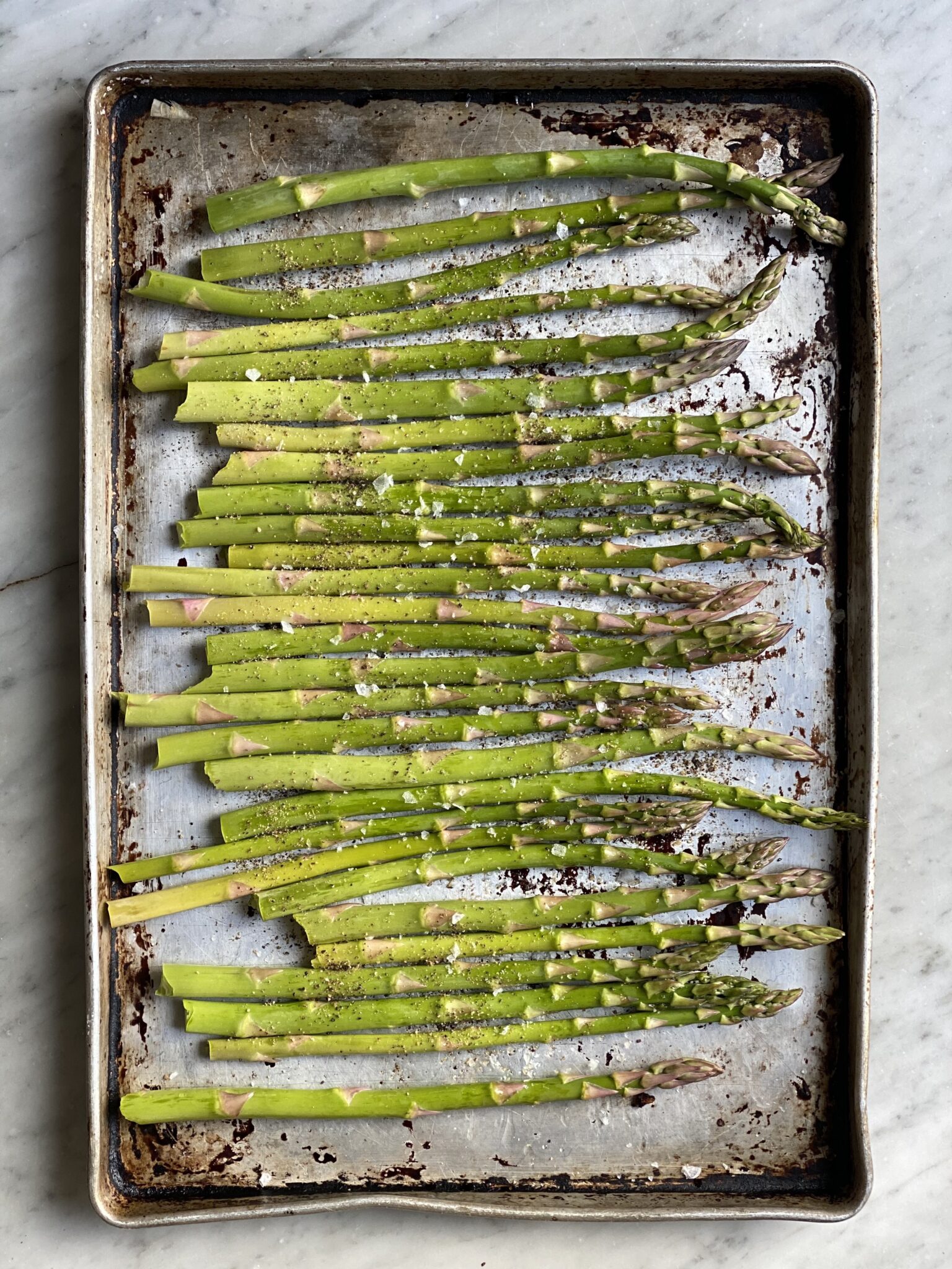 Asparagus on a cookie sheet with olive oil and salt and pepper