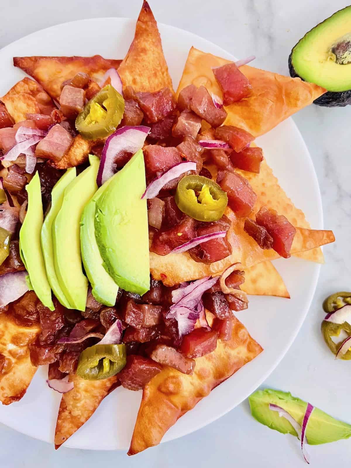 Ahi tuna poke nachos with avocado slices on a plate