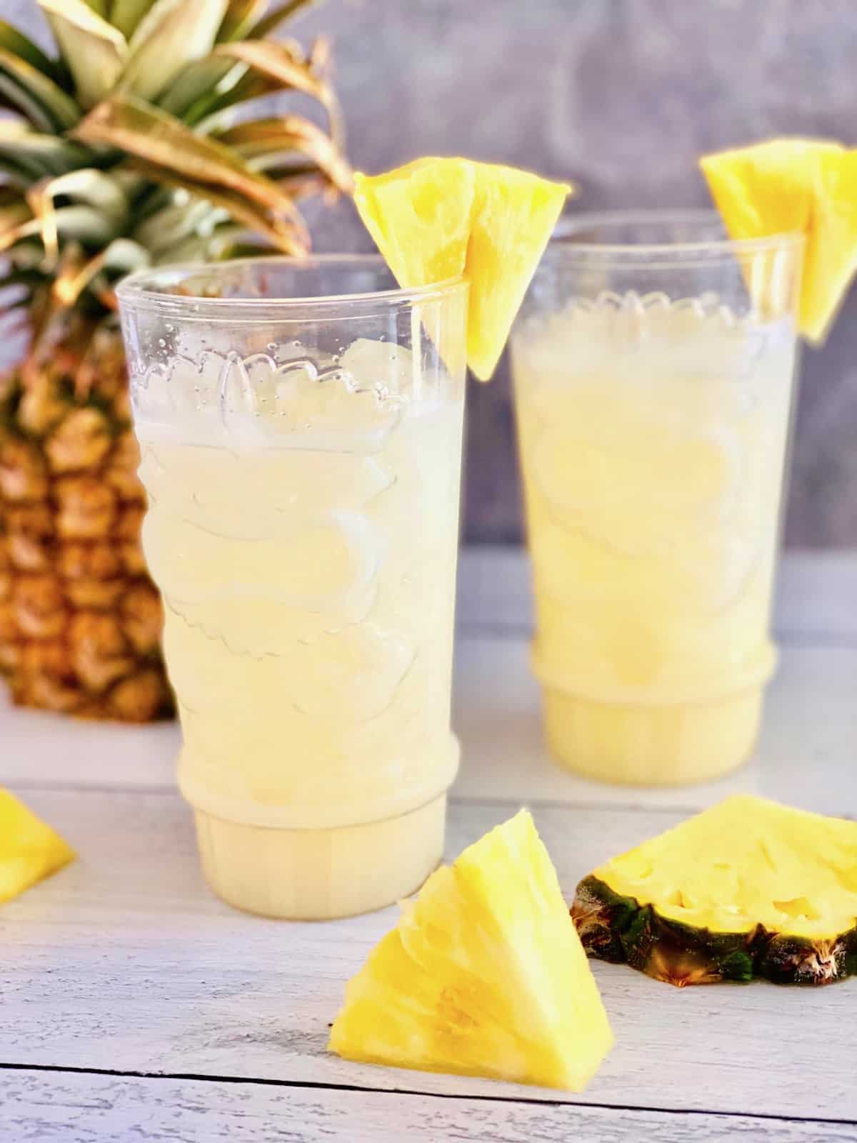 2 glasses of pina coladas on the rocks with pineapple slices