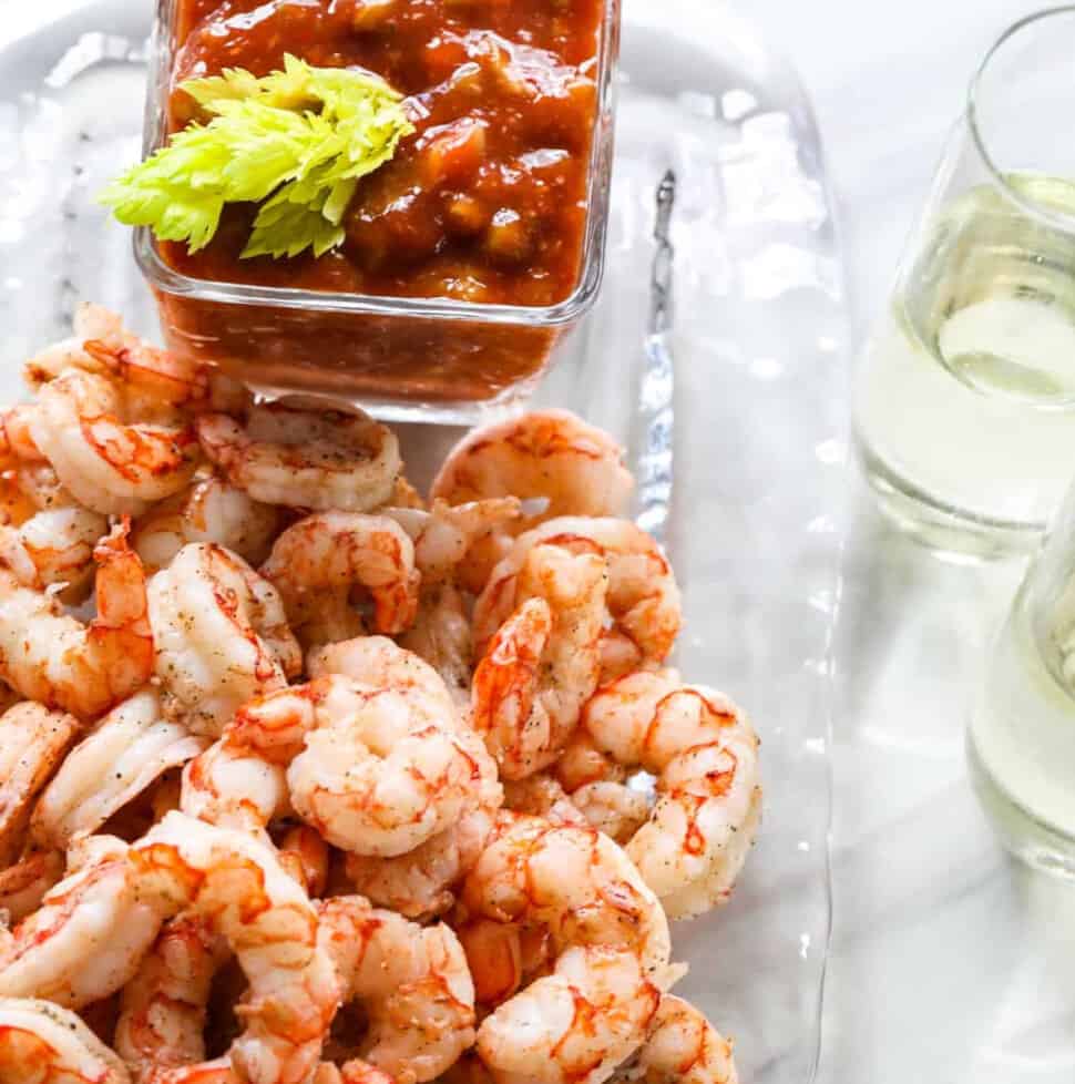 shrimp cocktail appetizer on a glass tray with 2 glasses of white wine