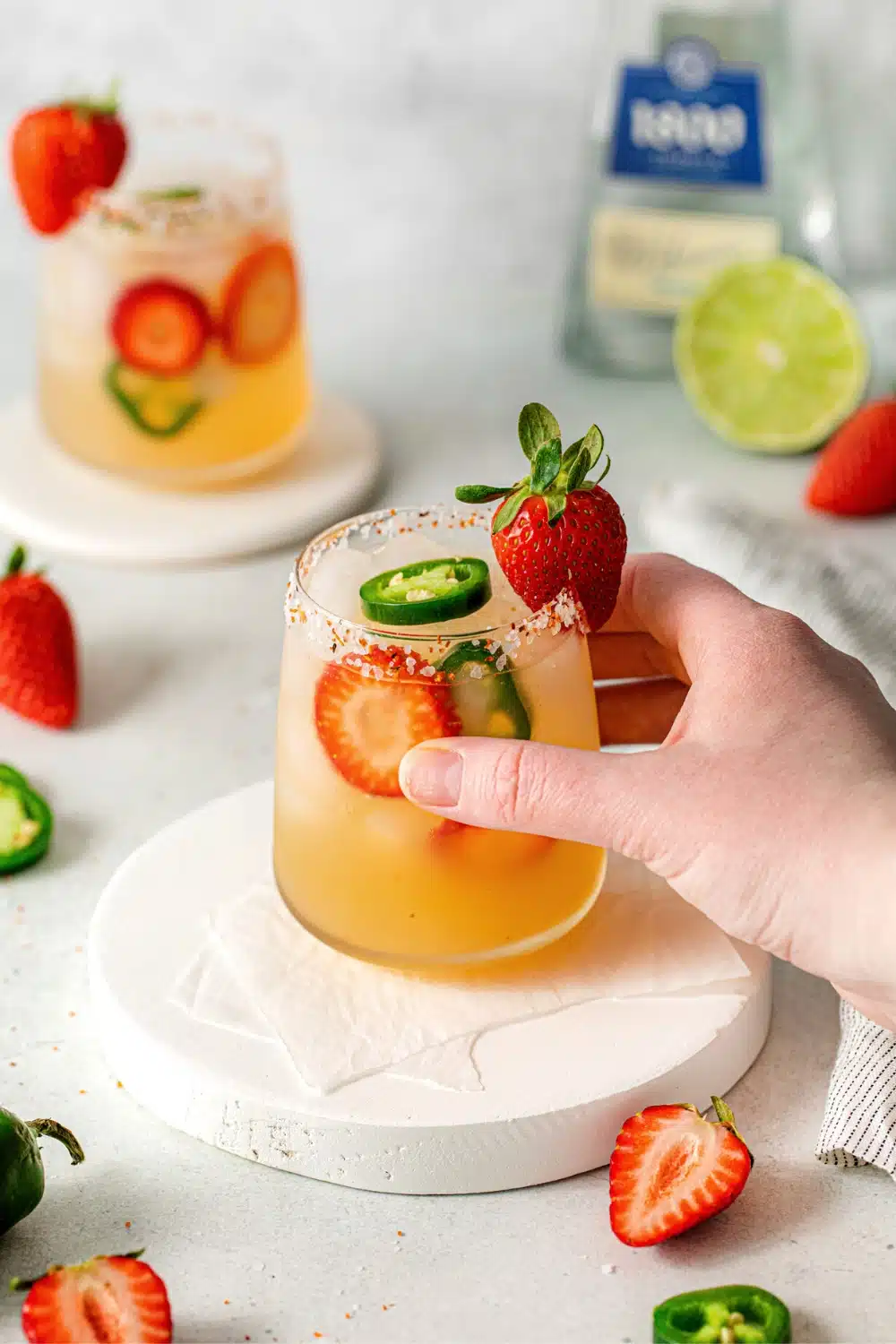 spicy strawberry jalapeno margarita with a hand grabbing it