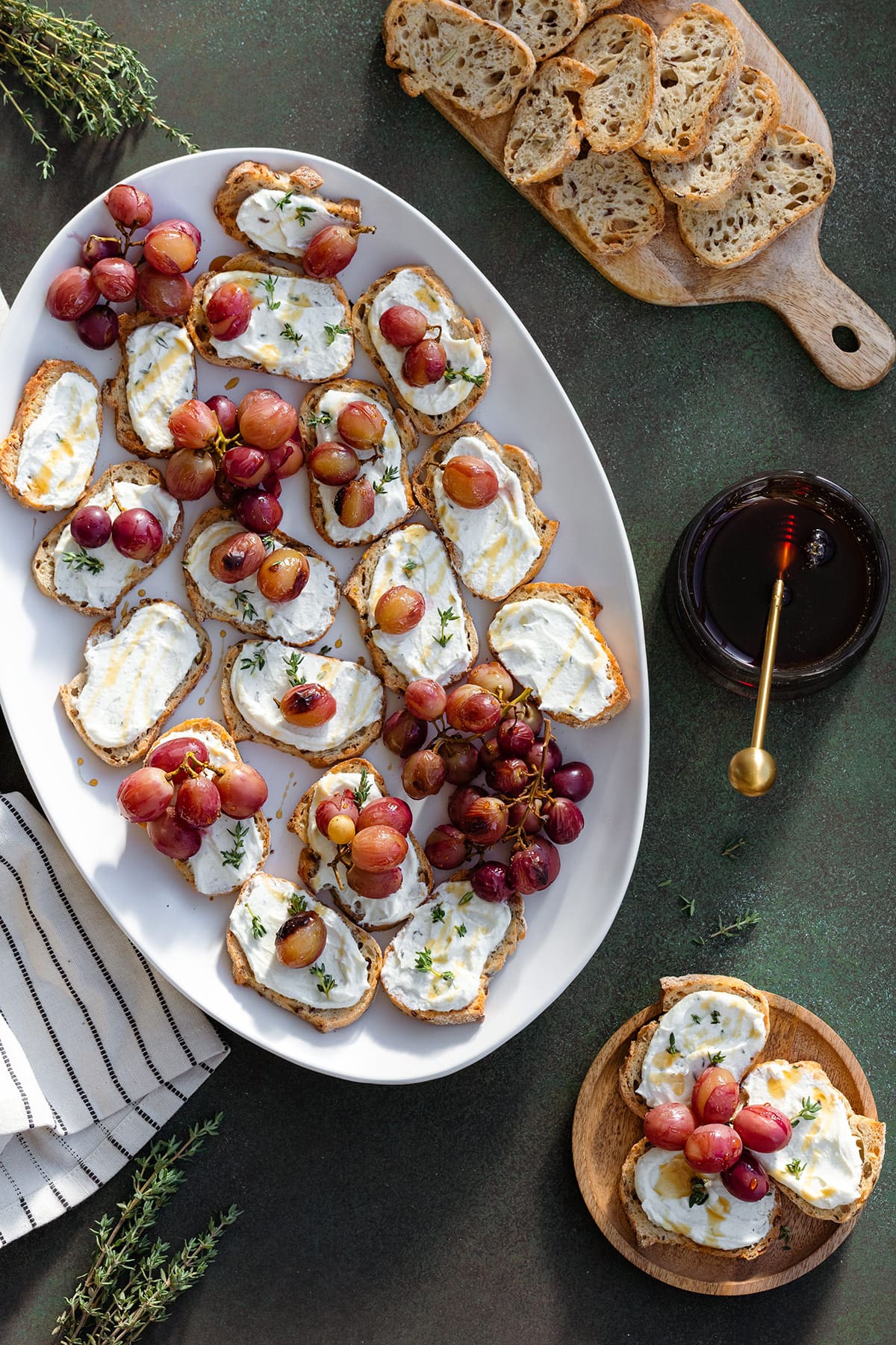Whipped Feta crostini with roasted grapes on a platter with honey