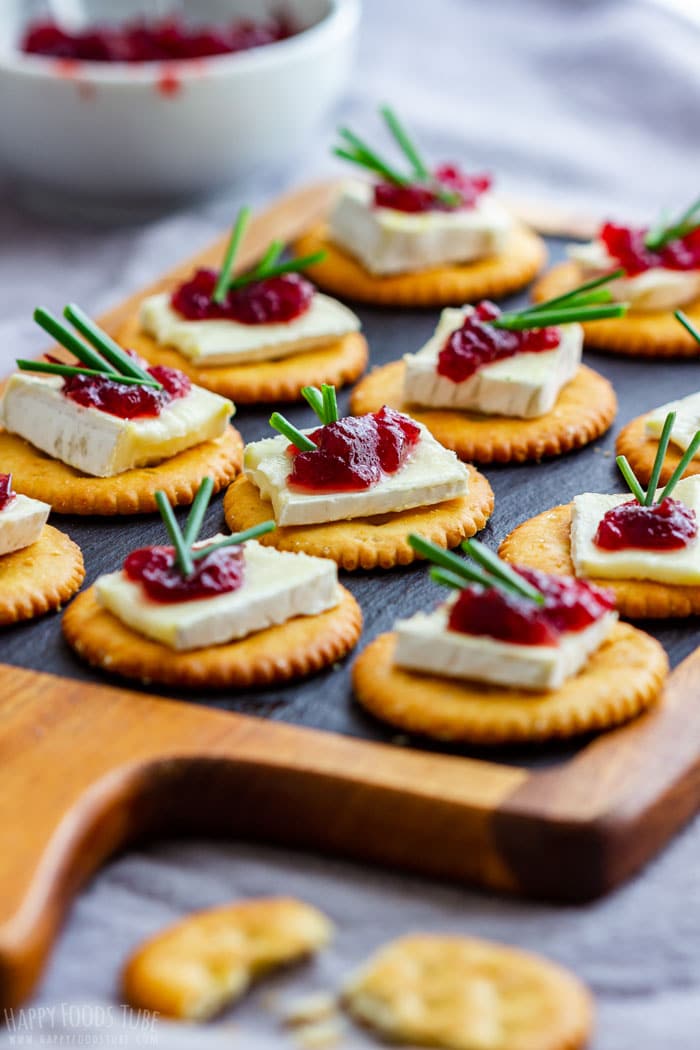 cranberry and brie bites with rosemarry on a wooden paddle