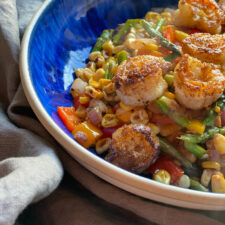 Shrimp power bowl with corn and asparagus and pepper and onions in a blue bowl