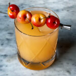 Summer Sea Breeze drink in a crystal glass with 4 cherries as a garnish.