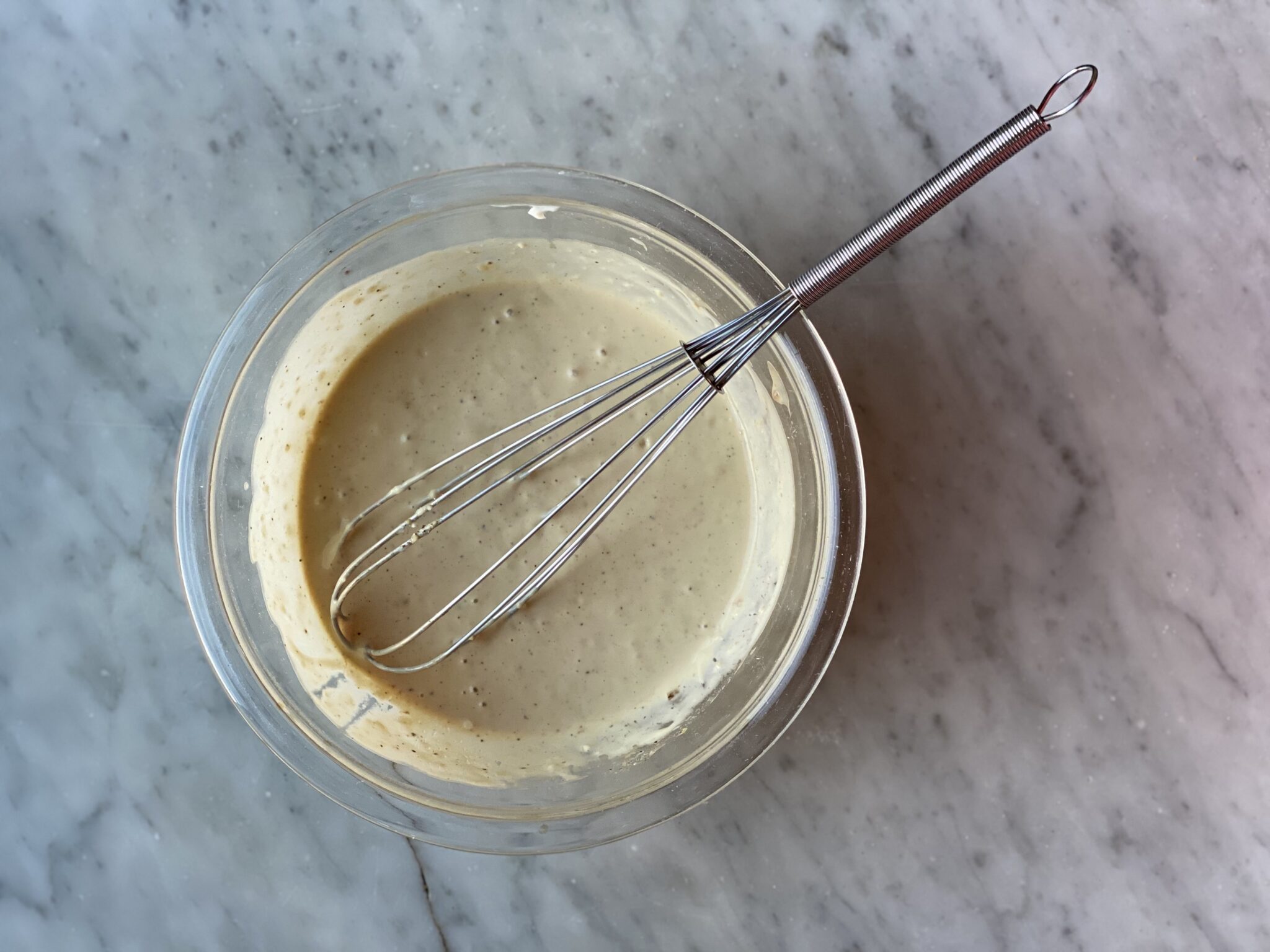 bowl of caesar dressing with a whisk