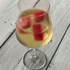 Watermelon ice cubes in a glass of wine
