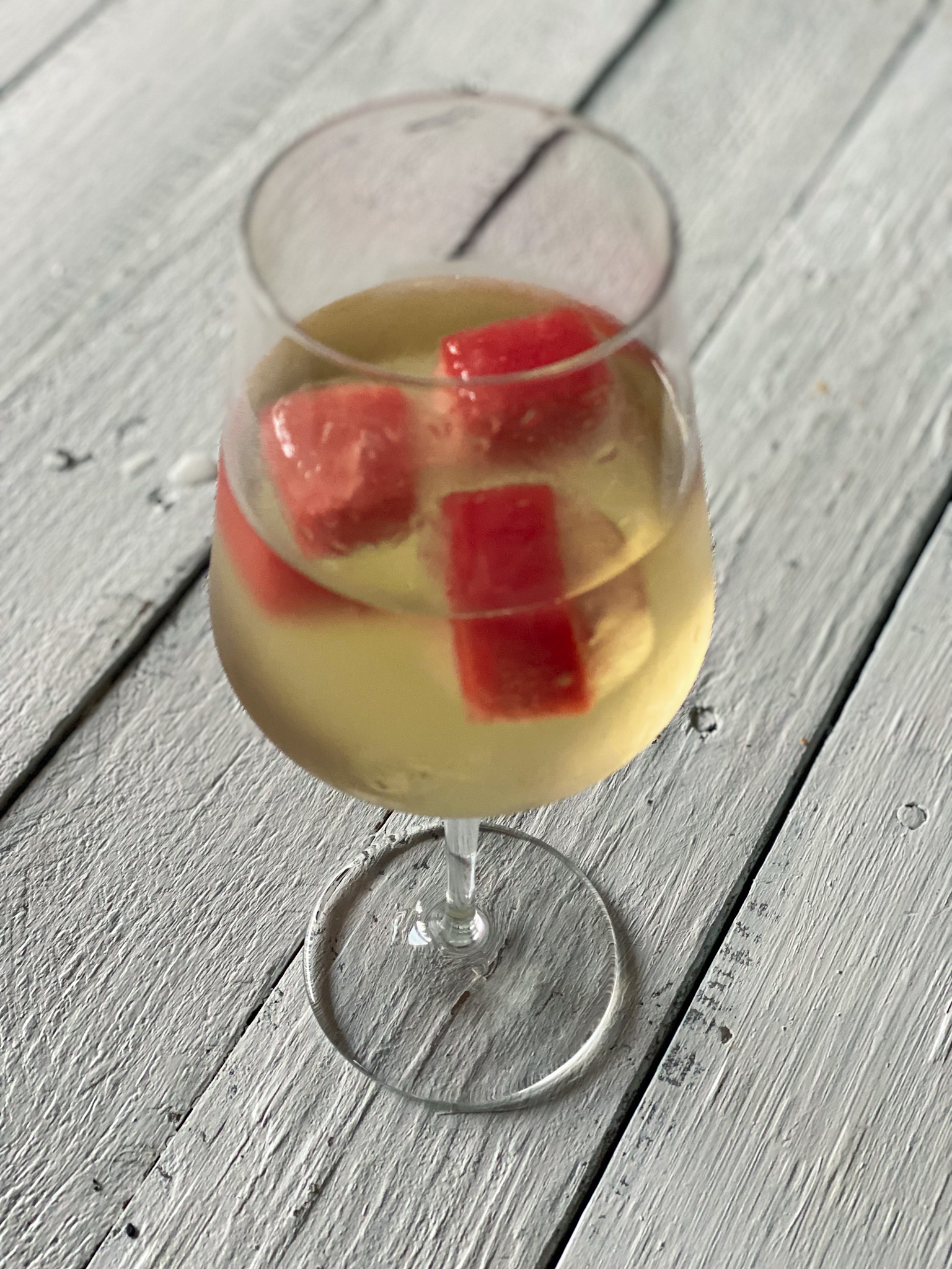 Watermelon ice cubes in a glass of wine