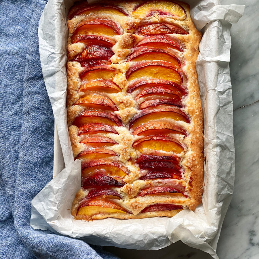 Peach topped cake in parchment with a blue napkin