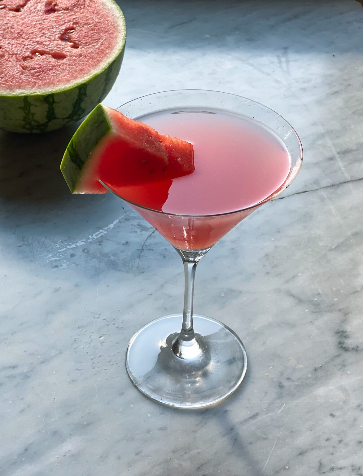 watermelon martini with a watermelon wedge and a watermelon in backround