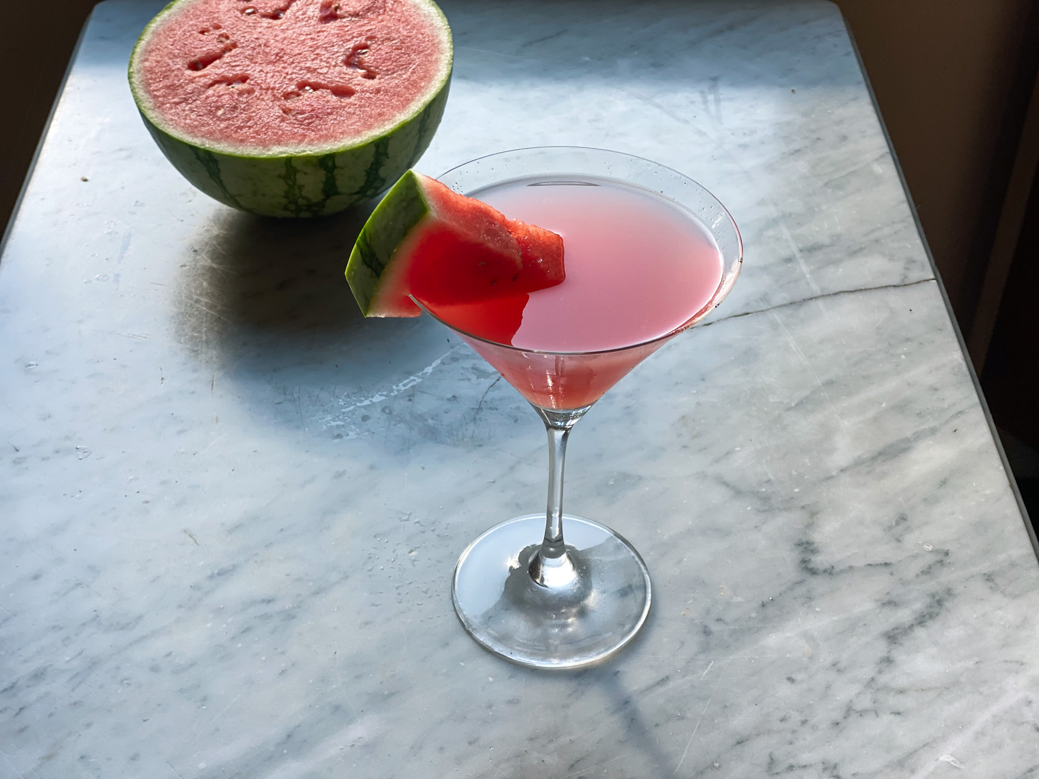watermelon martini with watermelon wedge and watermelon in backround