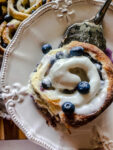 blueberry sweet roll with lemon cream cheese frosting being served onto a white plate