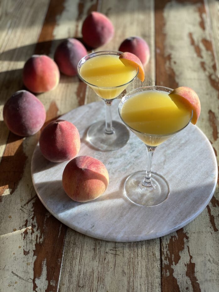 peach martinis on a marble round with peaches
