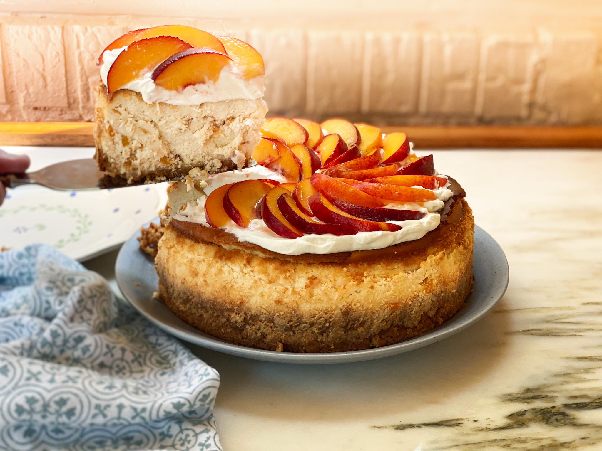 peach cheesecake with a slice out of it and a blue napkin