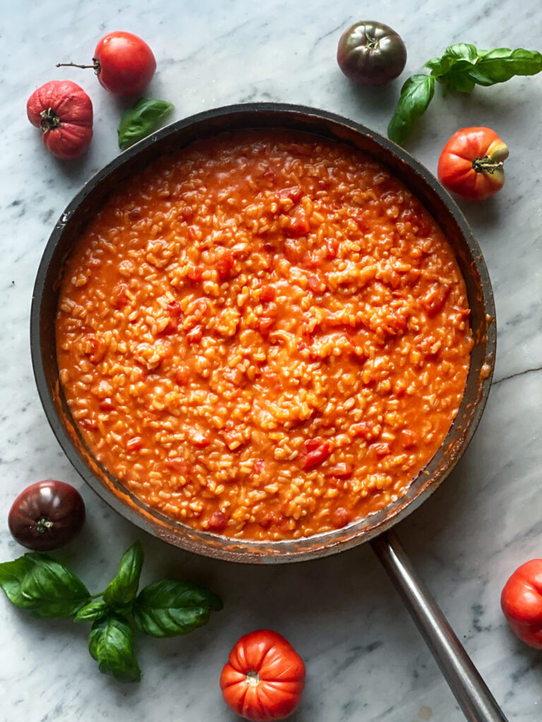 Tomato Risotto in pan with tomatoes around the pan