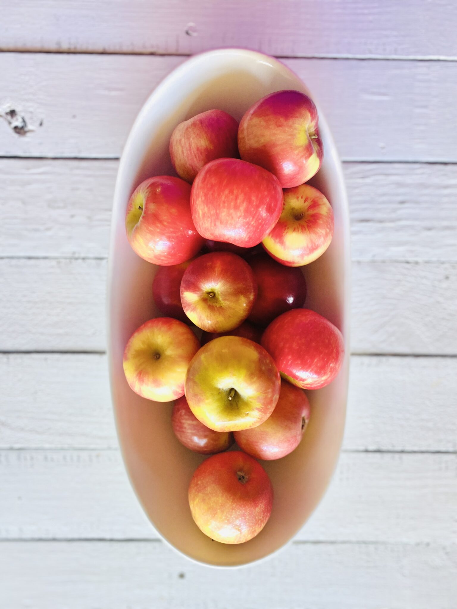 pink apples in a white bowl