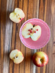 top view of a pink apple martini with apple and apple cut in half