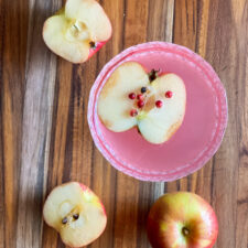 top view of a pink apple martini with apple and apple cut in half