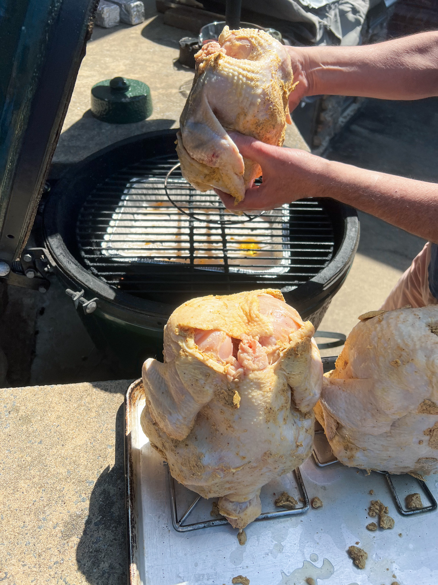 placing one chicken on the grill, with 2 waiting