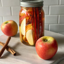 bourbon in a mason jar with apples and cinnamon sticks