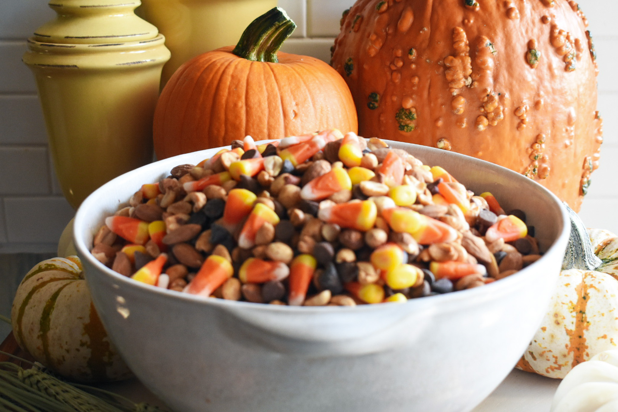 Big bowl of candy corn, peanuts, chocolate chips and almonds and pumpkins