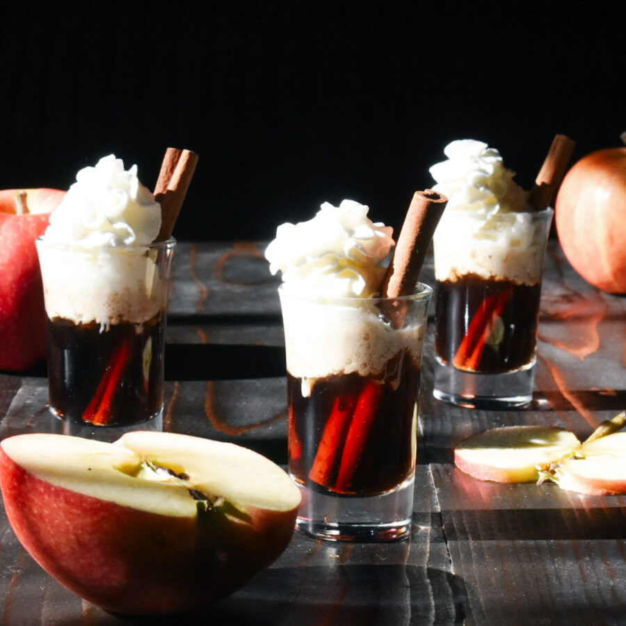 apple shots with whipped cream and cinnamon stick and apples
