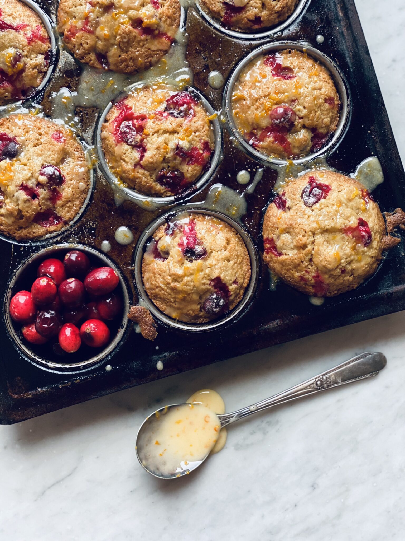 Cranberry orange muffins with glaze in a spoon